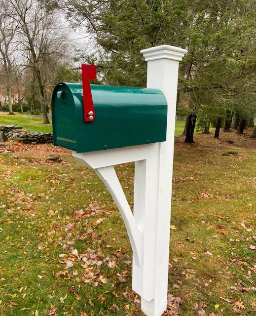 Green mailbox with red flag mounted on a handcrafted white post at a home in Fairfield, Connecticut.