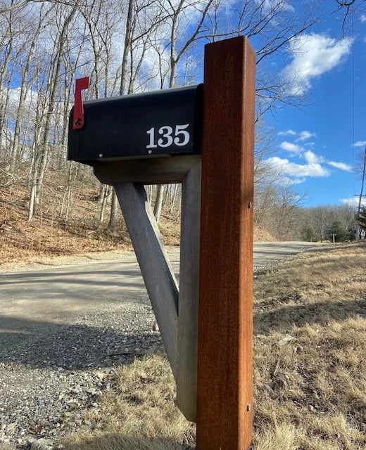 Black mailbox mounted on a handcrafted wooden post at a residential property in Roxbury, Connecticut.