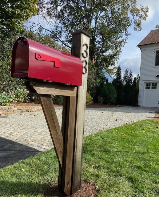 Red mailbox mounted on a handcrafted cedar post at a residential property in Westport, Connecticut.
