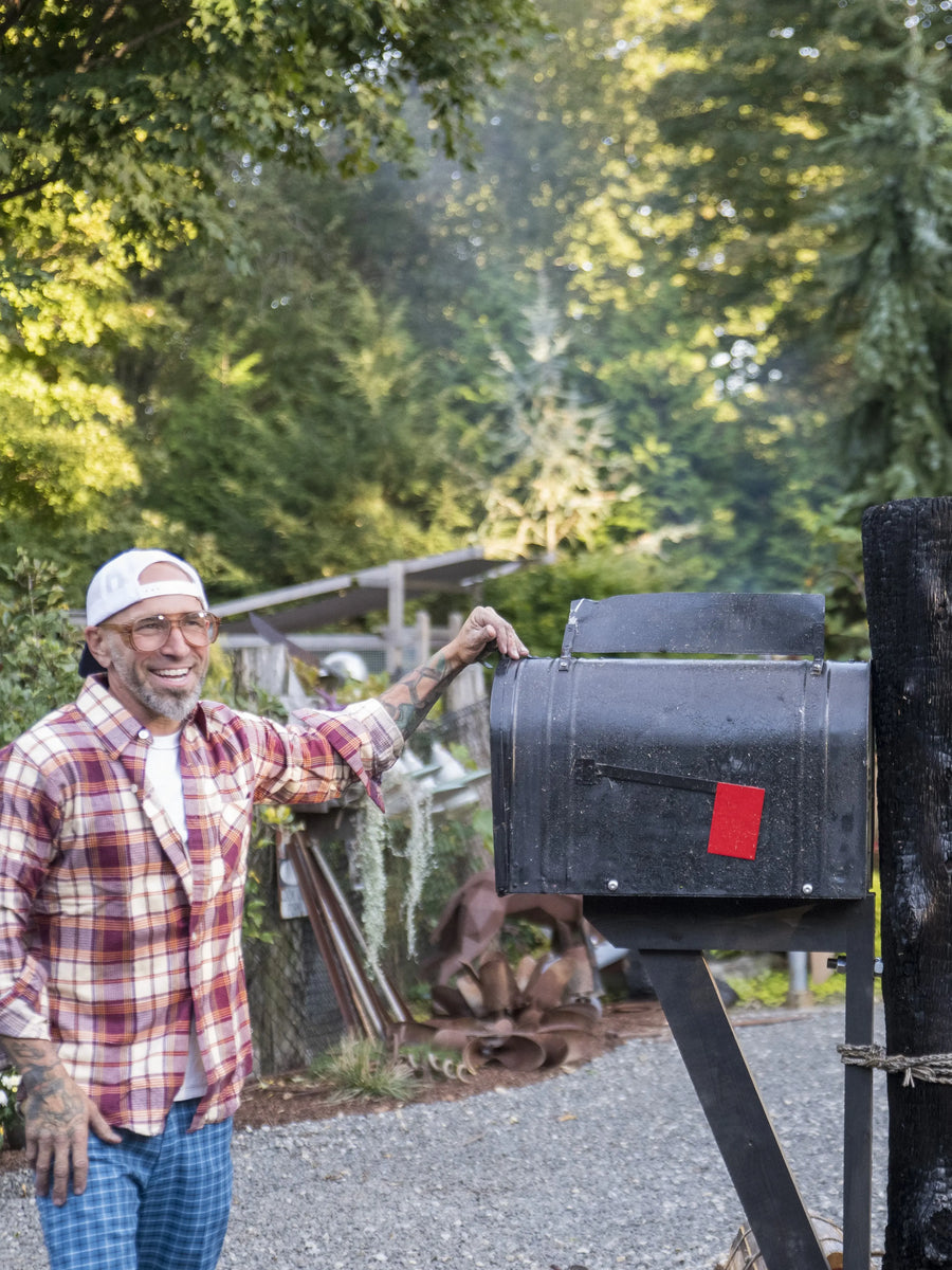 Garrett, founder of Mrs. Mailbox, surrounded by handcrafted mailbox designs in Connecticut.
