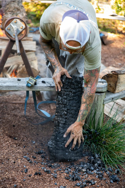 Garrett preparing charred cedar using a traditional wood-burning technique for handcrafted mailbox designs.