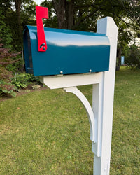 Angled front view of a teal blue mailbox set featuring a white pine post, solid cedar bracket, and bright red mailbox flag.