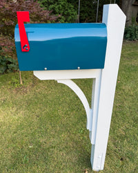 Full side view of a teal blue mailbox mounted on a white handcrafted post and curved bracket assembly in an outdoor setting.