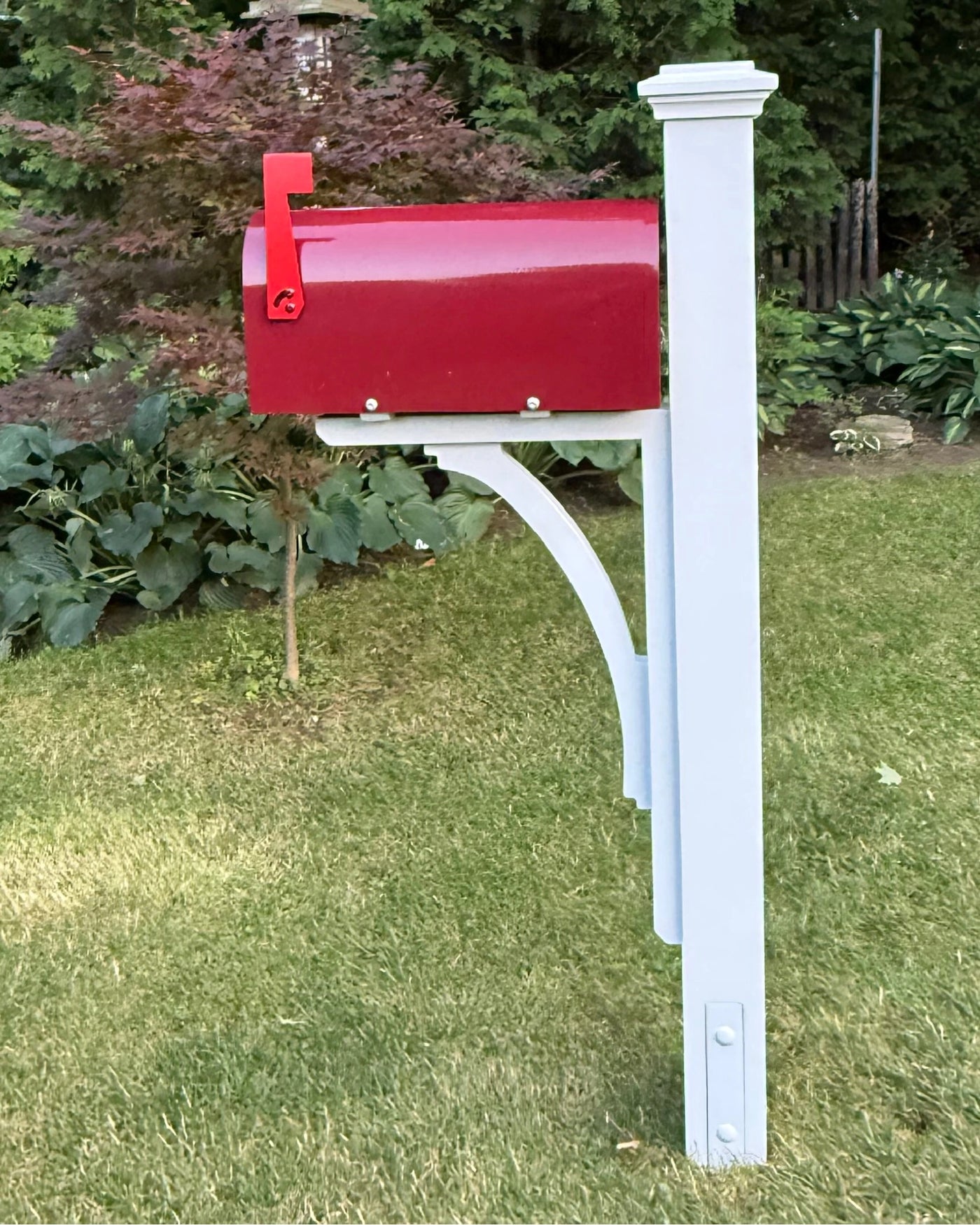 Full side view of a burgundy mailbox set featuring a white pine post, decorative post cap, and handcrafted curved cedar bracket.