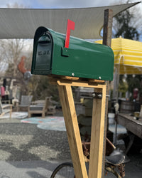 Full view of a modern aluminum mailbox set featuring a custom cedar bracket and patina steel post in an outdoor setting.