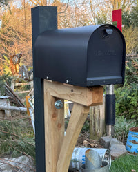 Angled view of a handcrafted black mailbox set featuring a cedar bracket assembly and durable steel core post in natural light.