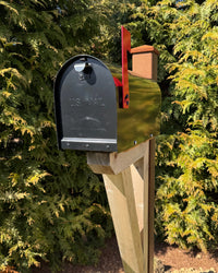 Side view of a black Titan vandal-resistant mailbox with natural cedar detailing and a weathered steel mounting post in sunlight.