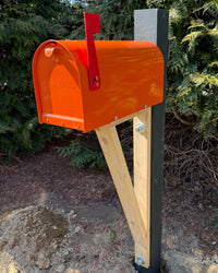 Orange Titan steel mailbox with red flag and handcrafted cedar detailing designed for durable outdoor curb appeal.