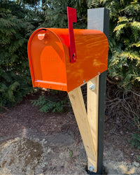 Front angle view of an orange Titan vandal-proof mailbox with cedar support bracket and painted structural post.