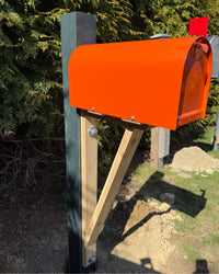 Side view of a bold orange Titan mailbox mounted on a cedar bracket with reinforced painted post construction.