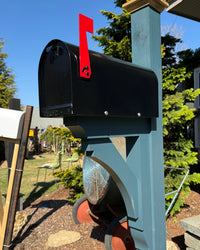 Angled view of a black Titan steel mailbox paired with a painted blue cedar post and handcrafted support bracket.