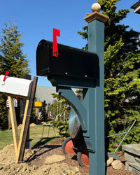 Full view of a modern black Titan mailbox set featuring a painted blue cedar post with handcrafted architectural bracket detailing.
