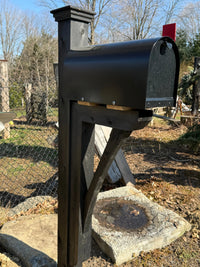 Close side view of a black Titan steel mailbox paired with a painted black cedar post sleeved over steel.