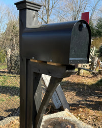 Side view of a modern black mailbox set featuring a painted cedar post, pyramid cap, and handcrafted support bracket.