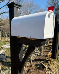 Full angled view of a modern white mailbox set featuring a black cedar post, black bracket detailing, and durable steel-reinforced construction.