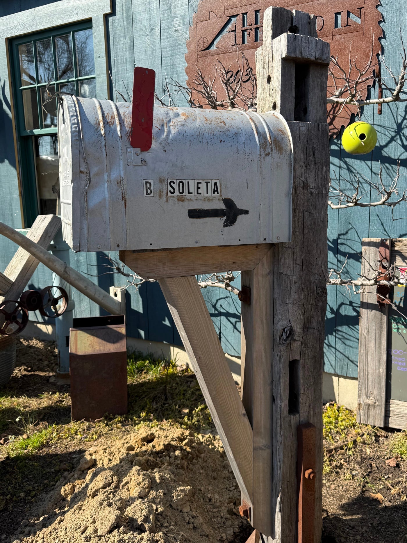 Side view of a weathered XL vintage mailbox paired with a reclaimed wood post and handcrafted cedar support bracket.