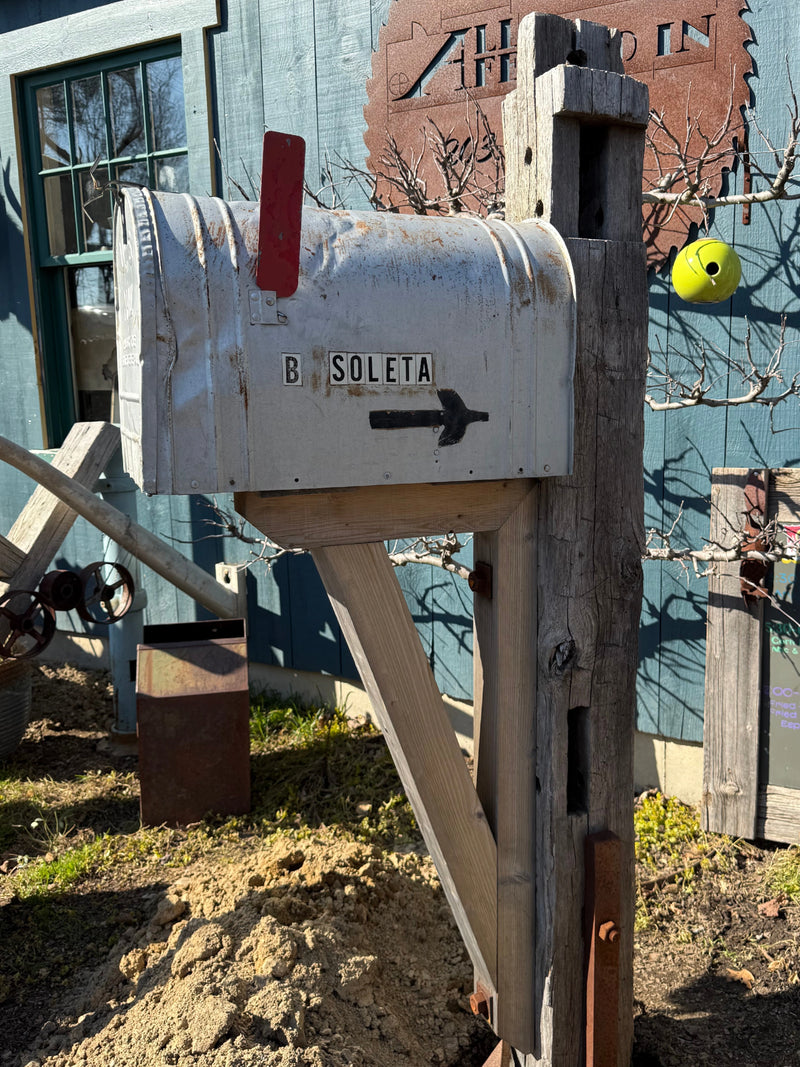 Side view of a weathered XL vintage mailbox paired with a reclaimed wood post and handcrafted cedar support bracket.