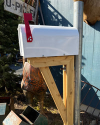 Front angled view of a white steel mailbox set featuring a galvanized post, layered cedar bracket, and durable handcrafted construction.