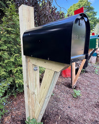 Close side view of a black Titan steel mailbox with a reinforced wood bracket and clean handcrafted construction.
