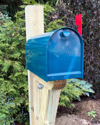 Side view of a teal Titan steel mailbox with a pressure-treated wood post and reinforced bracket assembly.