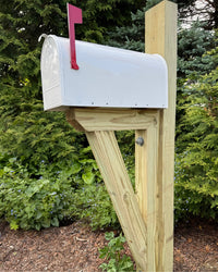 Front view of a black handcrafted mailbox set featuring a pressure-treated wood bracket and classic galvanized steel mailbox.