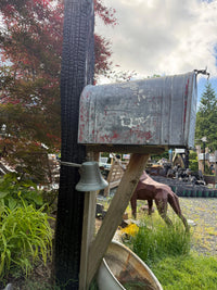 Close front view of a distressed vintage galvanized mailbox with aged texture and handcrafted rustic curbside design.