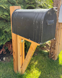 Side view of a rustic black vintage-style mailbox mounted on a handcrafted cedar post and reinforced angled support bracket.