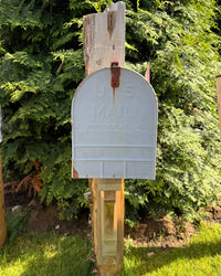 Front view of a weathered vintage XL mailbox mounted on a handcrafted cedar post with rustic handcrafted support bracket.