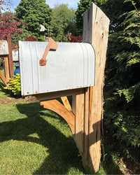 Side view of a vintage XL mailbox mounted on a handcrafted cedar post with decorative curved support bracket and rustic detailing.
