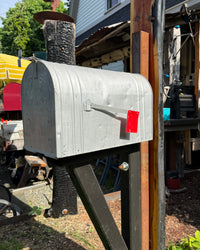 Low angle view of a handcrafted vintage mailbox set featuring blackened cedar support bracket and reinforced steel structure.