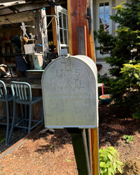 Side view of a vintage extra-large mailbox mounted on a handcrafted cedar and steel post with blackened support bracket and rustic detailing.