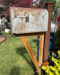 Side angled view of a handcrafted rural mailbox set featuring weathered metal textures, cedar bracket assembly, and reinforced steel post.