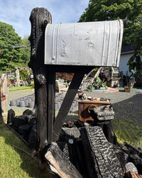 Close angled view of a handcrafted XL mailbox mounted on a charred cedar post with industrial black support structure and rustic detailing.